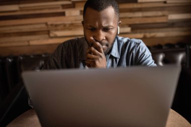 Yakışıklı genç adam masada oturuyor ve dizüstü bilgisayar kullanıyor. 