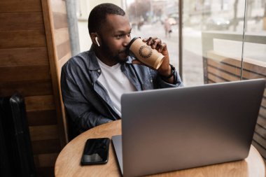 Kahveli ve dizüstü bilgisayarlı yakışıklı bir genç.  