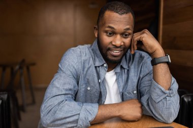 Masada oturan sıradan giysili yakışıklı bir gencin portresi.