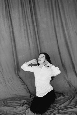 Beyaz elbiseli genç kadın döşemede oturuyor.