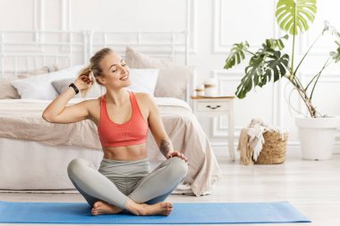 Oturma odasında yoga egzersizi yapan genç bir kadın. 