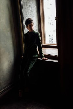 Pencere kenarında poz veren güzel genç bir kadın. 