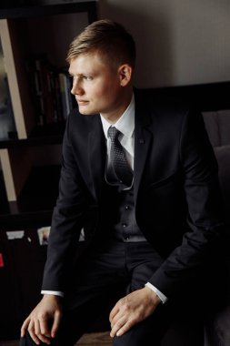 Stüdyoda poz veren zarif takım elbiseli yakışıklı genç adam.