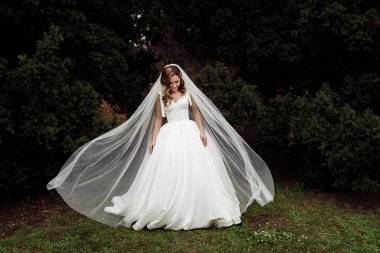 Açık havada poz veren zarif, genç bir gelin.