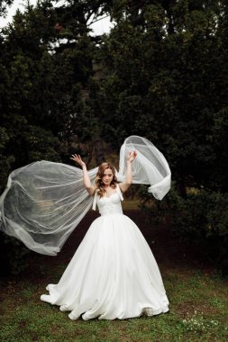 Açık havada poz veren zarif, genç bir gelin.