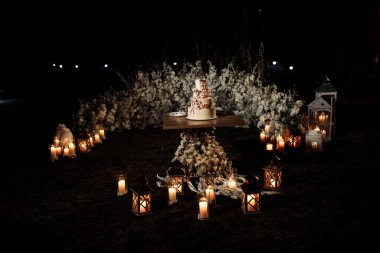 düğün pastası ve masa arkasında çiçekler.