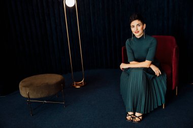 Stüdyoda sandalyede oturan güzel genç bir kadının portresi. 