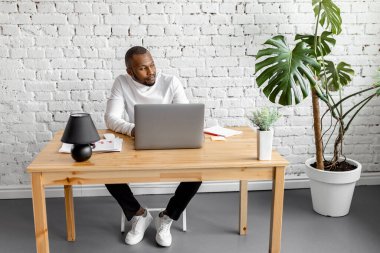 Ofisinde dizüstü bilgisayarı olan Afrikalı Amerikalı serbest yazar.