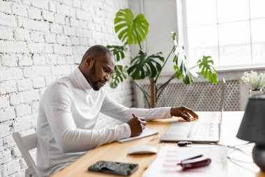 Ofisinde dizüstü bilgisayarı olan Afrikalı Amerikalı serbest yazar.