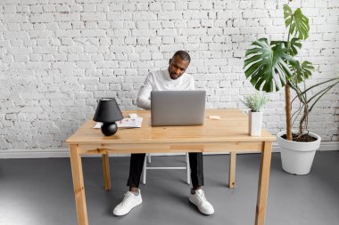 Ofisinde dizüstü bilgisayarı olan Afrikalı Amerikalı serbest yazar.