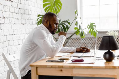 Ofisinde dizüstü bilgisayarı olan Afrikalı Amerikalı serbest yazar.