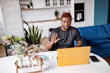 Masada dizüstü bilgisayarı olan Afrikalı Amerikalı bir adam var. 