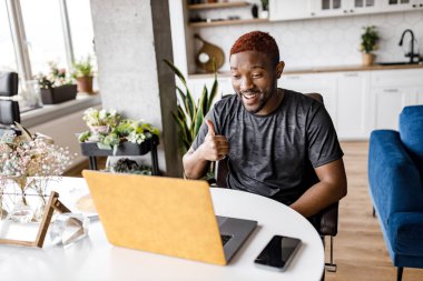 Masada dizüstü bilgisayarı olan Afrikalı Amerikalı bir adam var. 