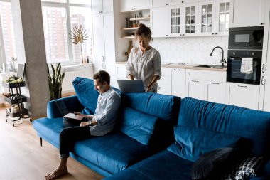 Evde dizüstü bilgisayar kullanan genç çift.