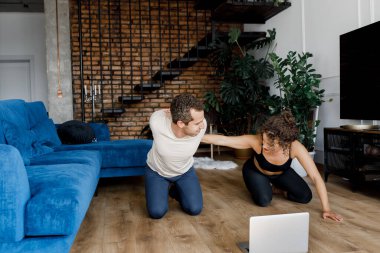 Genç çift evde dizüstü bilgisayarla antrenman yapıyor.