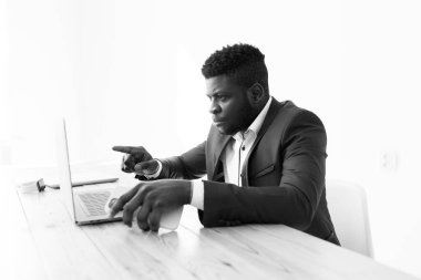 İş adamı masada oturuyor ve dizüstü bilgisayar kullanıyor.