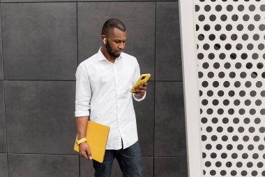 Şehirde dizüstü bilgisayarı ve akıllı telefonu olan Afrikalı genç bir Amerikalı.