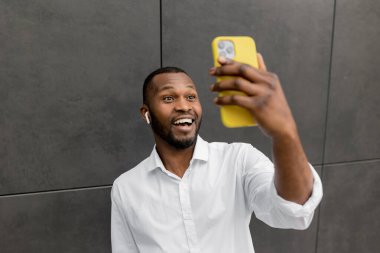 Cep telefonuyla selfie çeken Afrikalı yakışıklı Amerikalı adamın portresi. 