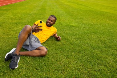 Stadyumdaki akıllı telefonlu genç formda adam. 