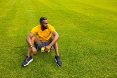 Stadyumdaki akıllı telefonlu genç formda adam. 