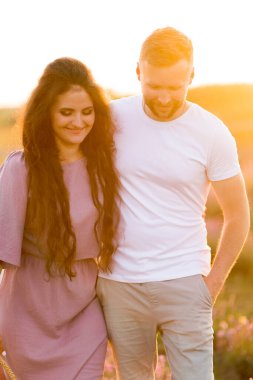 Aşık genç çift gün batımında tarlada dinleniyor. 