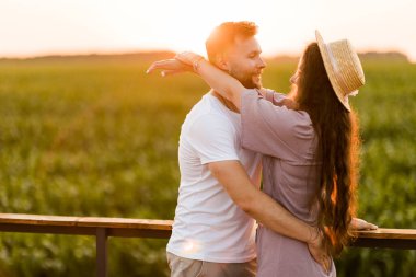 Aşık genç çift gün batımında tarlada dinleniyor. 