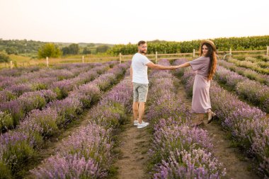 Aşık genç çift gün batımında tarlada dinleniyor. 