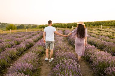 Aşık genç çift gün batımında tarlada dinleniyor. 