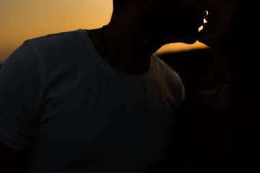 Genç çift gün batımında tarlada öpüşüyor. 