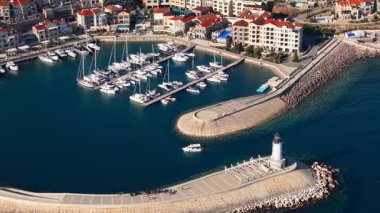 Karadağ 'da yat ve deniz feneri sergileniyor. Yakınlardaki parlak binalar kıyı manzarasına ekleniyor.