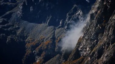 Karadağ 'ın yüksek dağları Prokletije, yeşil yamaçlar ve kamera tavaları, sis ve sonbahar yaprakları arasında dar bir dağlık vadi görünüyor.