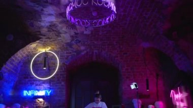 Genç ve güzel bir kız neon tabelalar yapar. Sanatçı mavi pembe güzel bir stüdyoda çalışıyor. Oda çok renkli neonlarla süslenmiş..