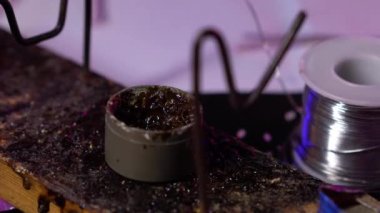 Lehim demiri, kabloları birbirine bağlamak için reçineyle işleniyor. Bir kavanoz reçine ve yakın plan elektrikli lehim ucu..