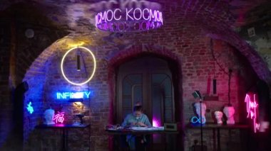Genç ve güzel bir kız neon tabelalar yapar. Sanatçı mavi pembe güzel bir stüdyoda çalışıyor. Oda çok renkli neonlarla süslenmiş..