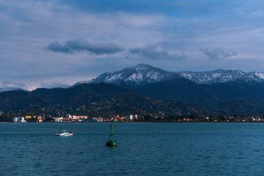 Mavi denizde güzel bir manzara, dağlar ve bulutlar. Georgia, Batumi 'deki limanda dalgalar üzerinde sallanıyor.