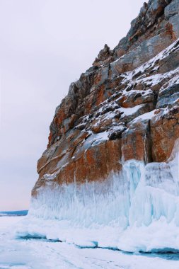 Baykal Gölü, kış günü. Olkhon Adası 'ndaki yüksek uçurumlar. Büyük buz blokları dağların eteklerini kaplıyor..