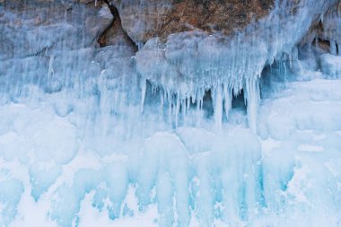 Güzel turkuaz buz sarkıtları kayayı kaplıyor. Baykal Gölü 'ndeki bir mağarada renkli buz..