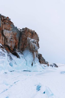 Baykal Gölü, kış günü. Olkhon Adası 'ndaki yüksek uçurumlar. Büyük buz blokları dağların eteklerini kaplıyor..