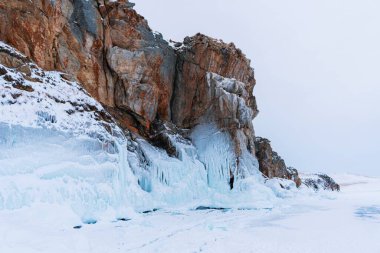 Baykal Gölü, kış günü. Olkhon Adası 'ndaki yüksek uçurumlar. Büyük buz blokları dağların eteklerini kaplıyor..