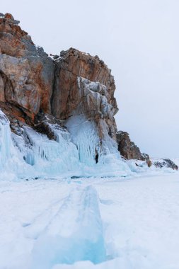 Baykal Gölü, kış günü. Olkhon Adası 'ndaki yüksek uçurumlar. Büyük buz blokları dağların eteklerini kaplıyor..