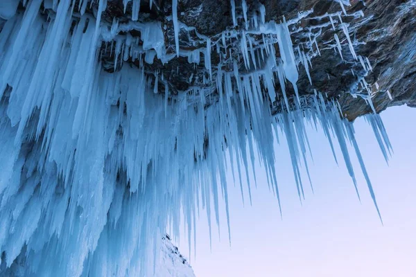 Increíble roca cubierta de hielo. La cueva helada está cubierta con grandes carámbanos en el lago Baikal. Fotos de stock libres de derechos