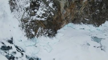 Kayanın ayağı güzel mavi buzla kaplıdır. Baykal Gölü 'nde kış. Donmuş göl, derin çatlakları olan buz..