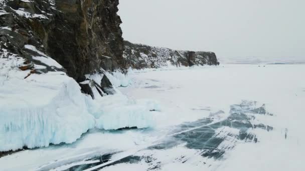 岩石的脚被美丽的蓝冰覆盖着 贝加尔湖的冬天冰冷的湖面 冰封着深深的裂缝 — 图库视频影像