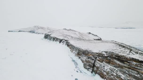 贝加尔湖上的岛屿湖上蓝色透明的冰部分被雪覆盖着 冰层上深裂的漂亮鸟瞰 — 图库视频影像