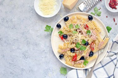 Ton balıklı, domatesli, zeytinli ve açık arkaplanda parmesan peynirli fusilli makarna. Kopyalama alanı olan üst görünüm. Sağlıklı yemek..