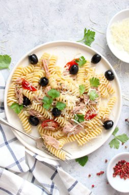 Ton balıklı, domatesli, zeytinli ve açık arkaplanda parmesan peynirli fusilli makarna. Kopyalama alanı olan üst görünüm. Sağlıklı yemek..