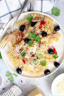 Ton balıklı, domatesli, zeytinli ve açık arkaplanda parmesan peynirli fusilli makarna. Kopyalama alanı olan üst görünüm. Sağlıklı yemek..