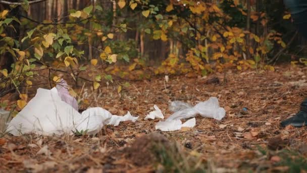 Un uomo getta spazzatura da un sacco di plastica nella foresta — Video Stock