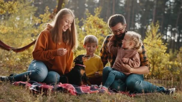 Gelukkig gezin met kinderen en een hond in een herfstpark — Stockvideo