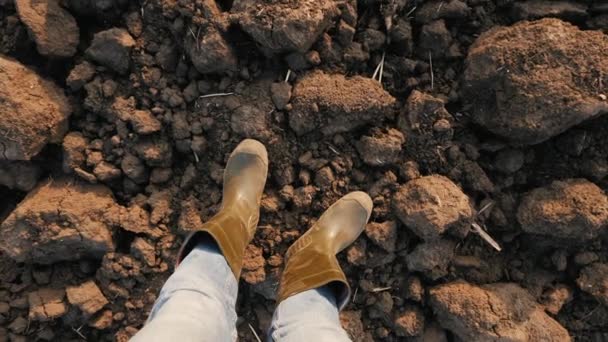 Top vista granjero macho en botas de goma de pie en el campo arado — Vídeo de stock
